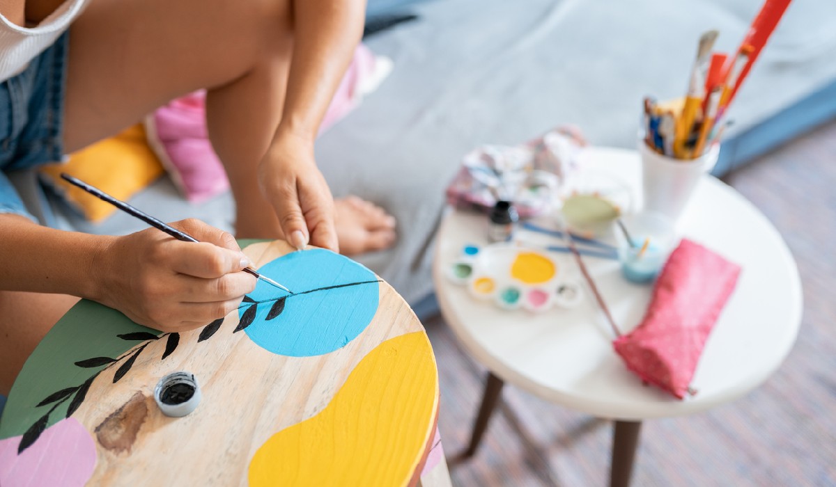 Woman painting a wooden bench at home