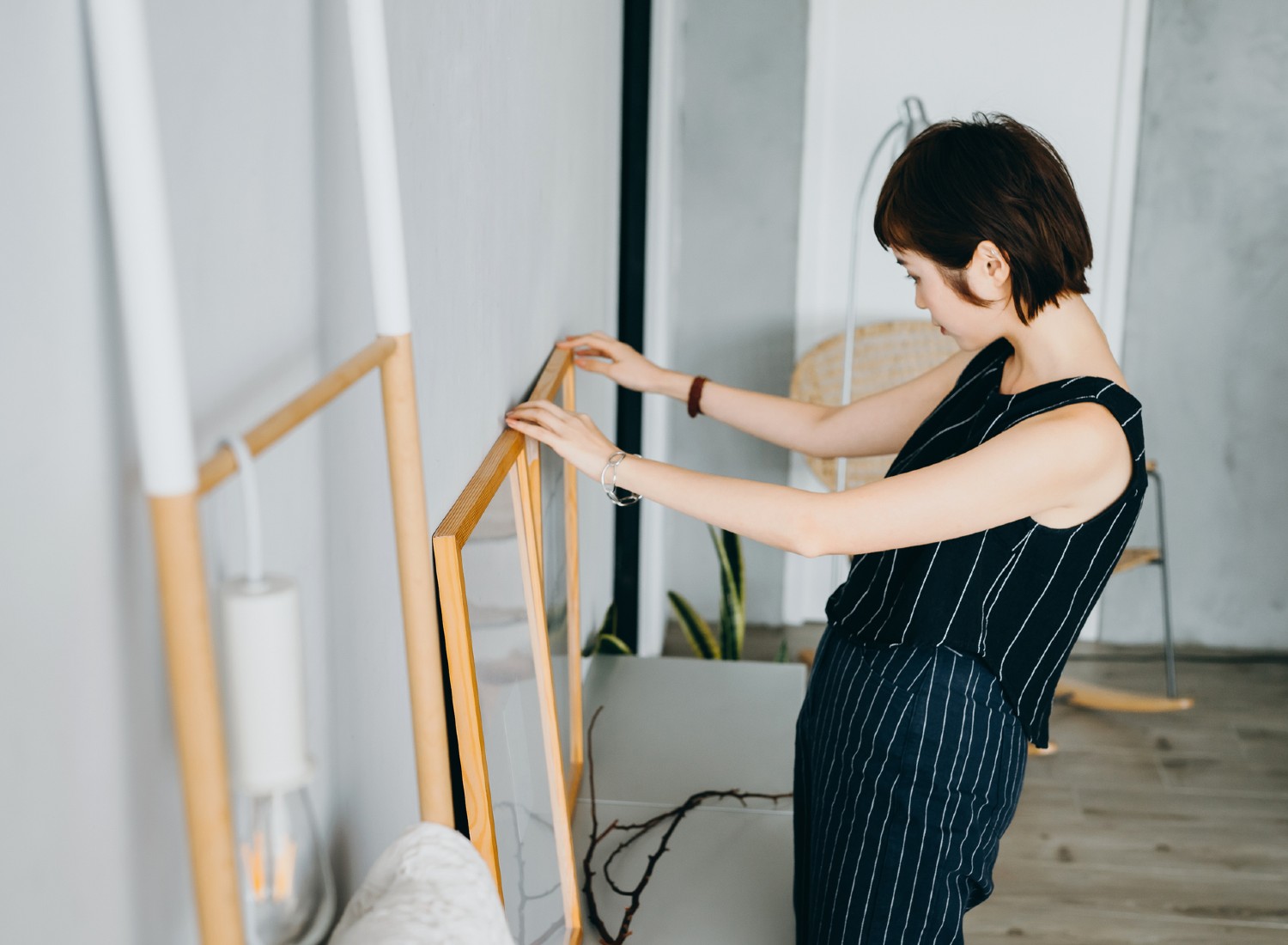 oung Asian woman decorating and organising picture frames on cabinet in the living room