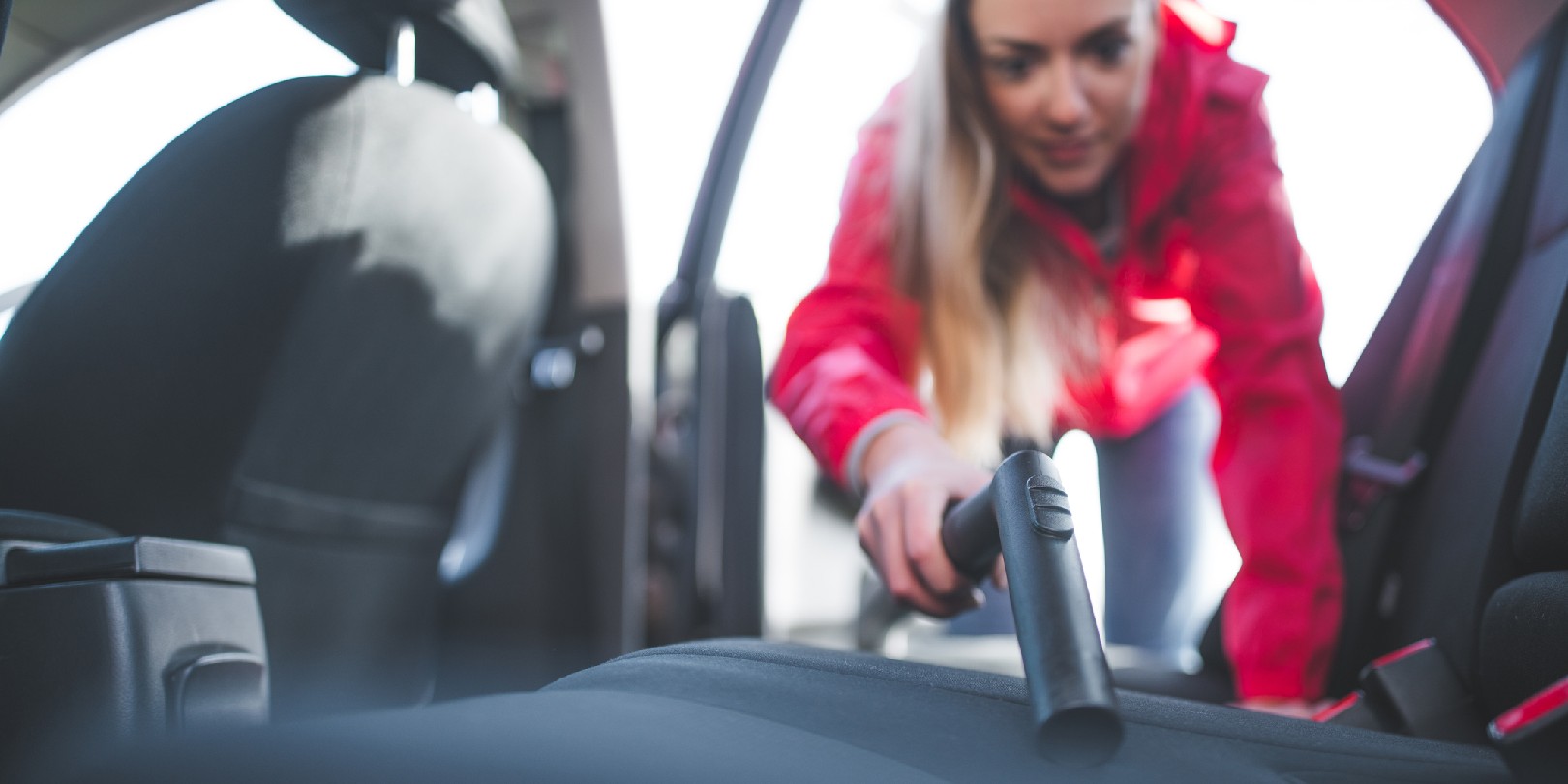 get-dog-hair-out-of-a-car the-independence Young woman is cleaning car with vacuum cleaner