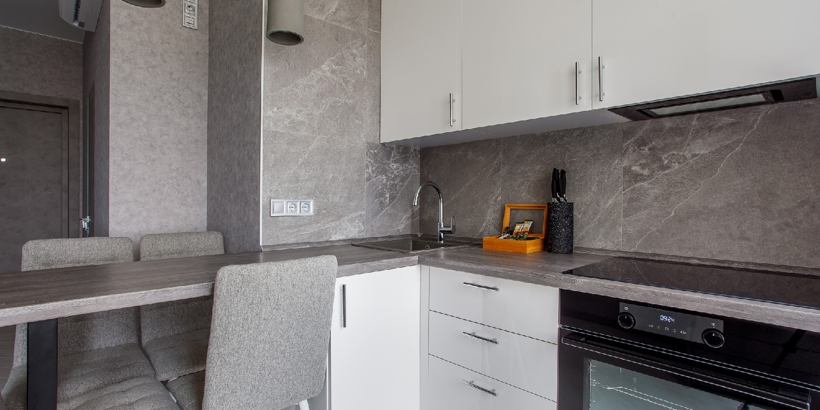 small-galley-kitchen the-independence Cooking area by the window with lots of white and beige cabinets, countertop, sink, kitchen appliances by a tiled marble wall.