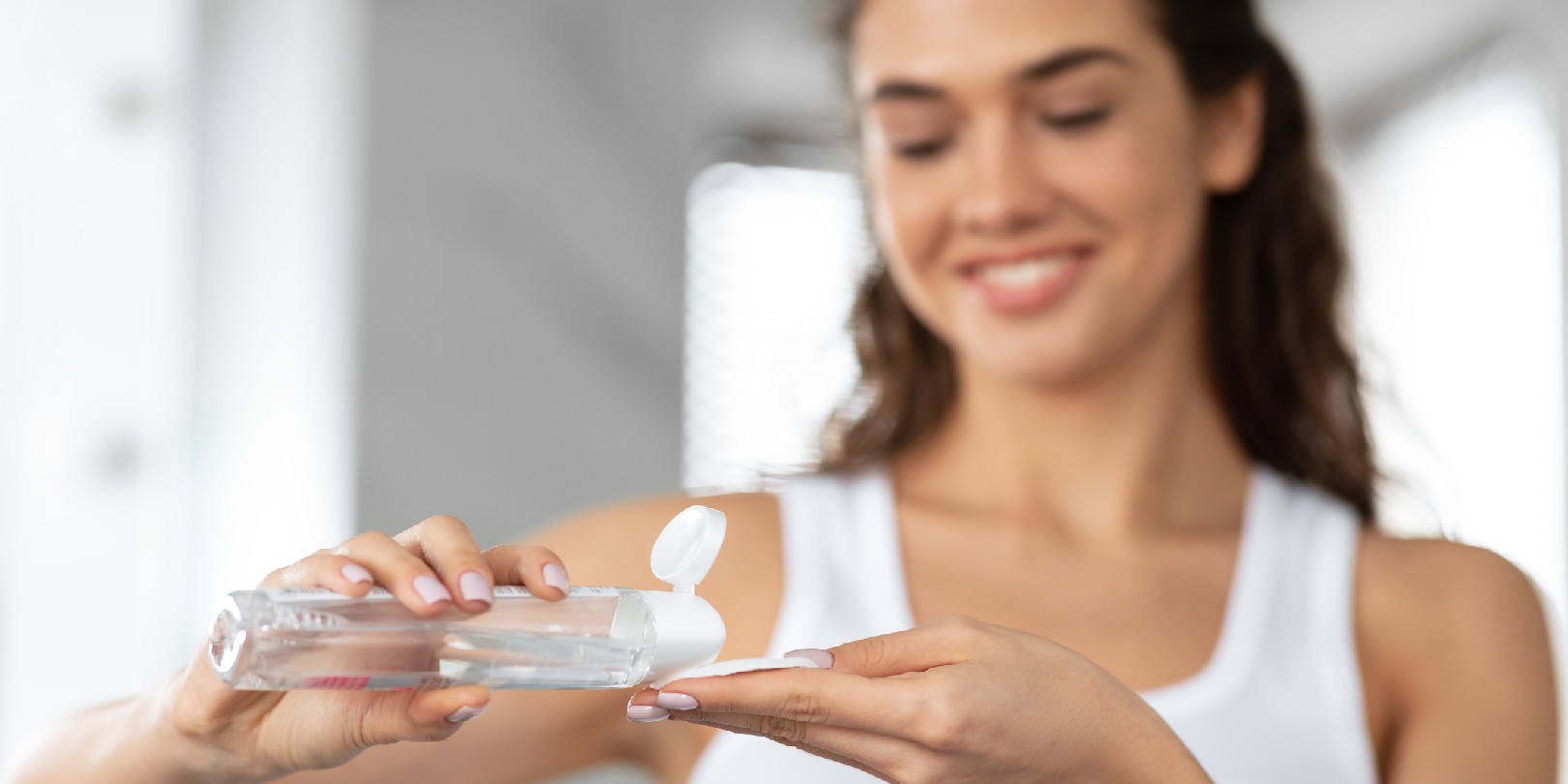 Young Woman Applying Micellar Water On Cotton Pad In Bathroom