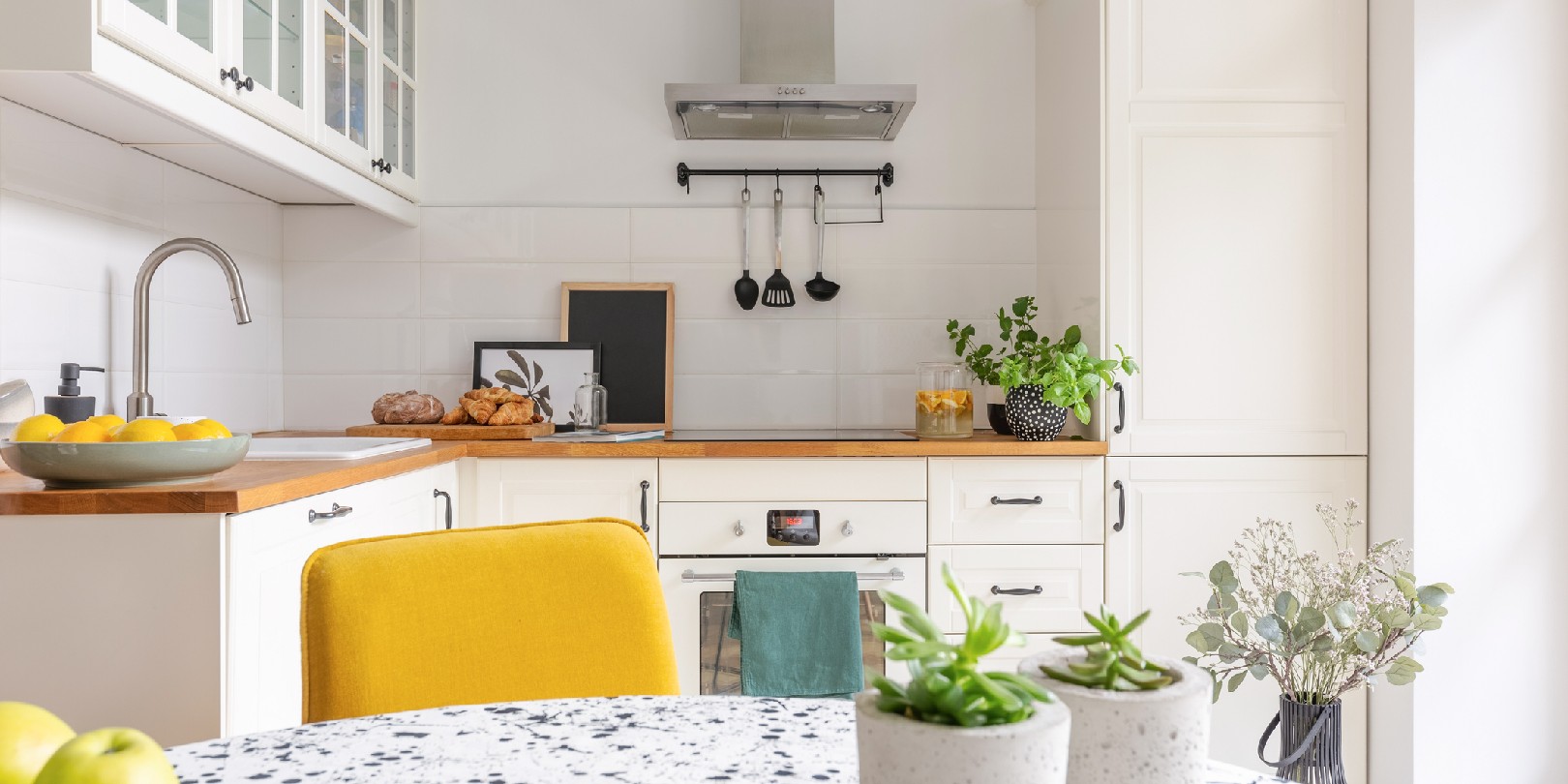 yellow-kitchen the-independence Plants in pots on the table in stylish white kitchen interior, real photo
