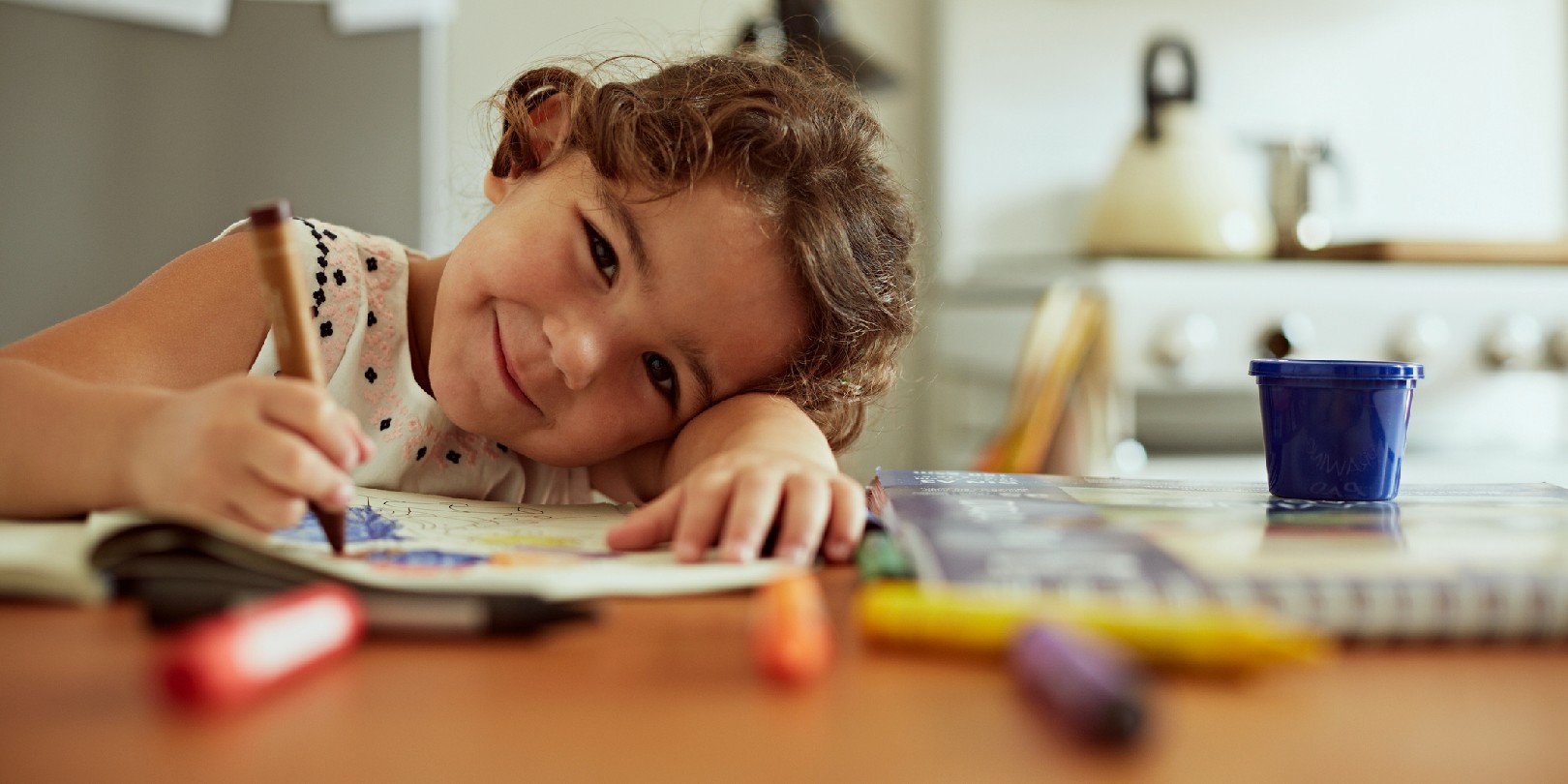 Portrait of little girl drawing in kitchen