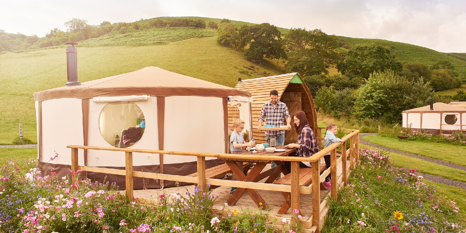 young family sit outside their yurt tent in wales