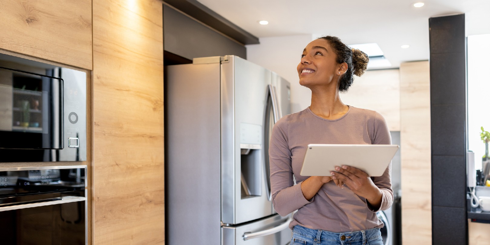 Happy woman controlling the lights of her smart house using an automated system from a tablet computer