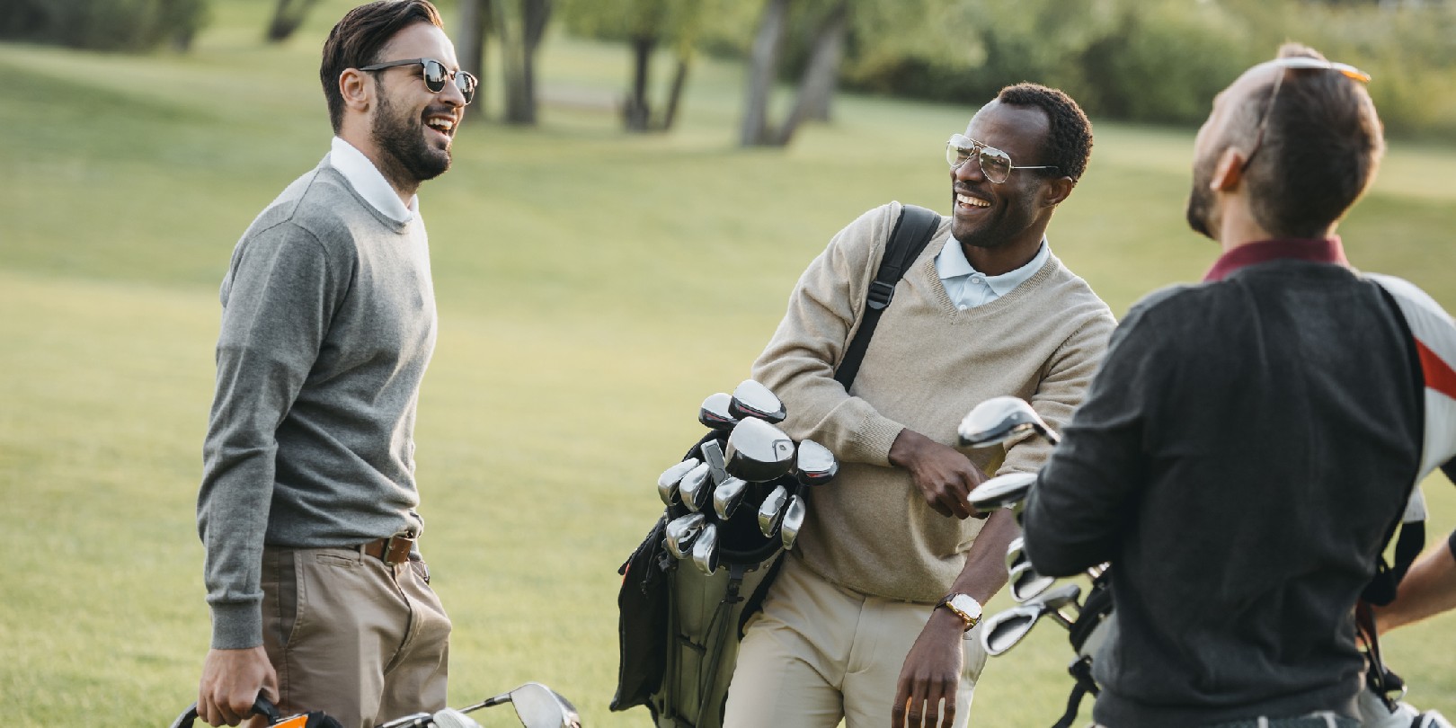 multiethnic golf players with golf clubs having fun on golf course
