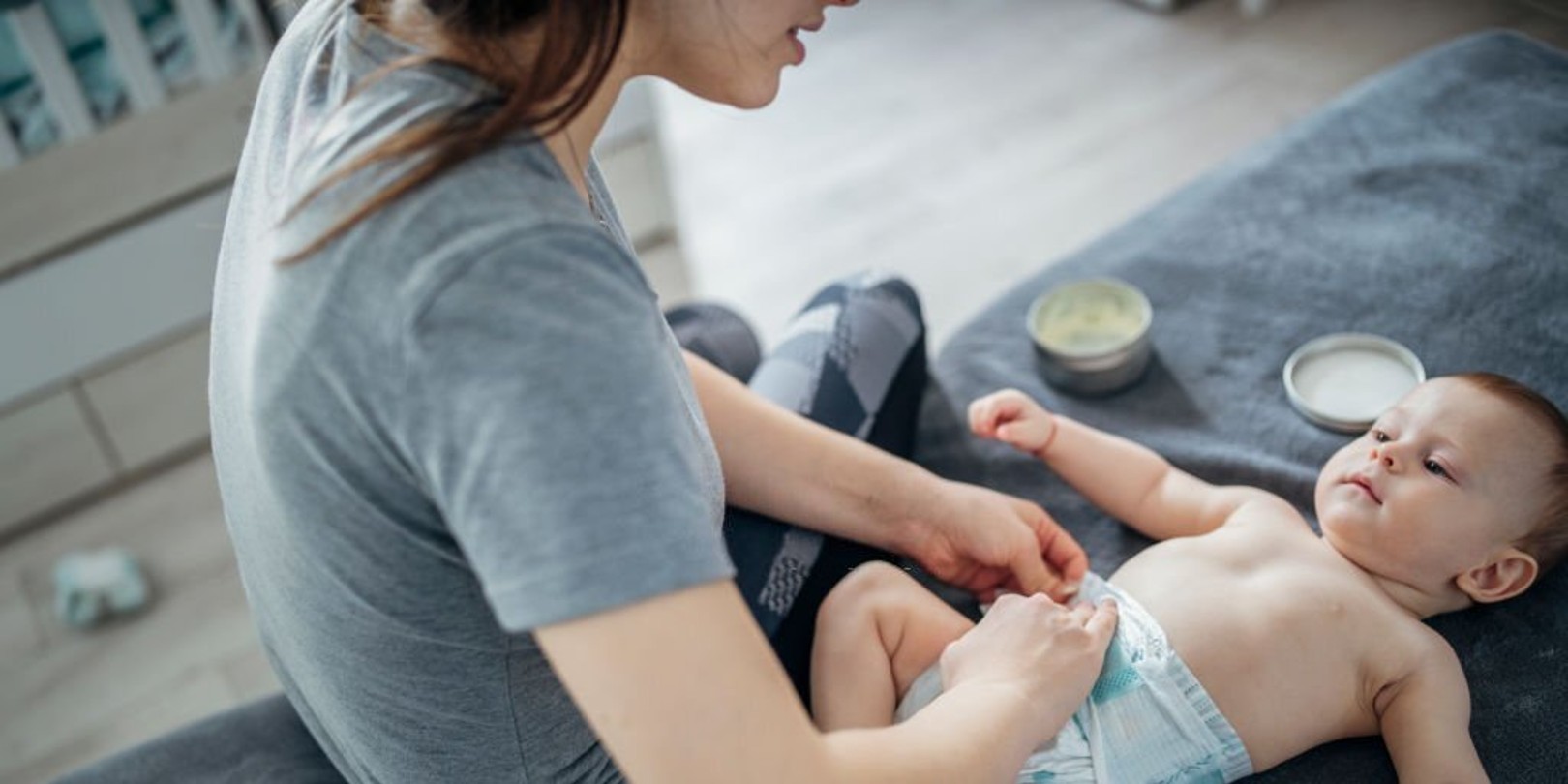 Baby boy having his diaper changed by his mother.