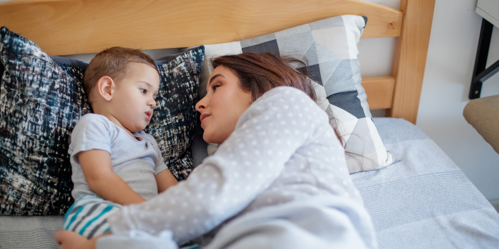 Mother cuddling with her toddler in bed